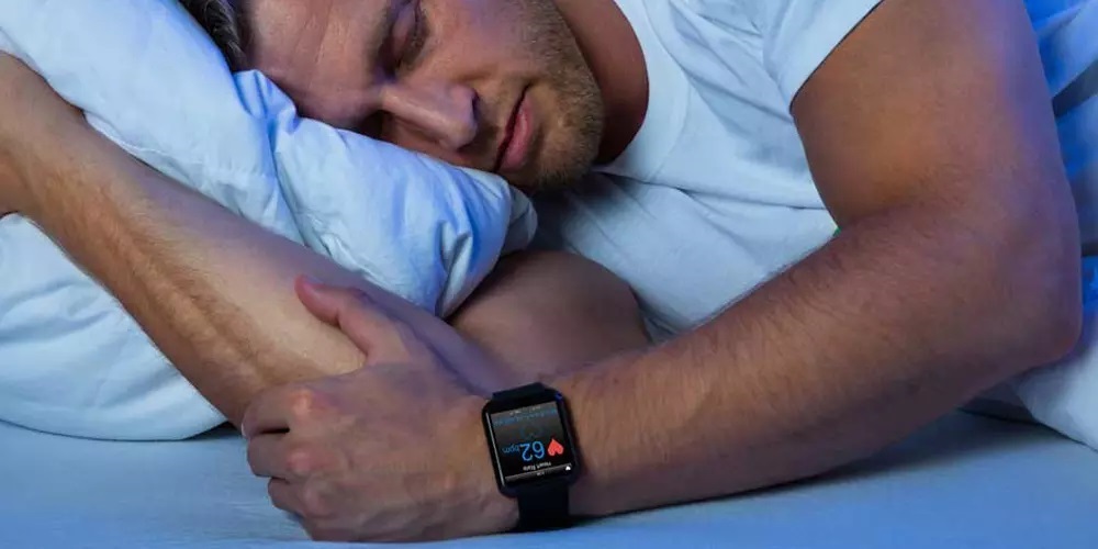 Hombre durmiendo mientras su reloj monitoriza su sueño